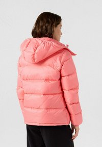 Giacca imbottita rosa con cappuccio, caratterizzata da trapuntatura orizzontale, polsini elasticizzati e chiusura con zip. Il materiale appare liscio e lucido.