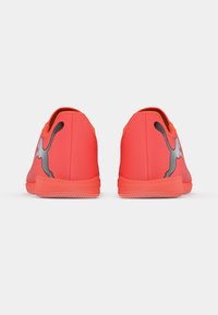 Lyse røde sportssko med en tekstureret finish og sorte accenter. Har en glat, afrundet ryg og en fleksibel gummisål.