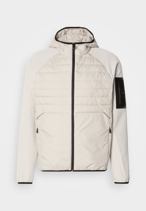 Hooded lightweight jacket in cream with quilted front, black zipper, and side pockets, featuring a zippered arm pocket with black accents.