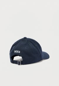 Granatowa czapka bejsbolówka wykonana z bawełny, posiada zakrzywiony daszek i regulowany pasek. Na tylnej części biała haftowana nazwa "BOSS".