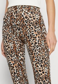 Luipaardprint legging met een rekbare stof, levendige oranje en zwarte patronen, en een gladde textuur, met een hoge tailleband.