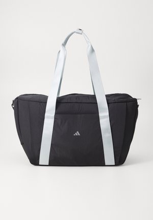 Black tote bag with light blue straps, zippered closure, subtle logo on front, structured shape, and smooth, textured fabric.
