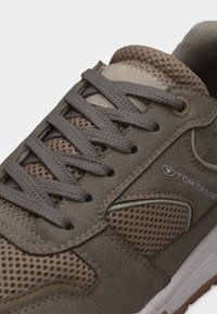 Grå og brun Tom Tailor sneaker med stofmeshpaneler, teksturerede snørebånd og en hvid gummisål detalje.
