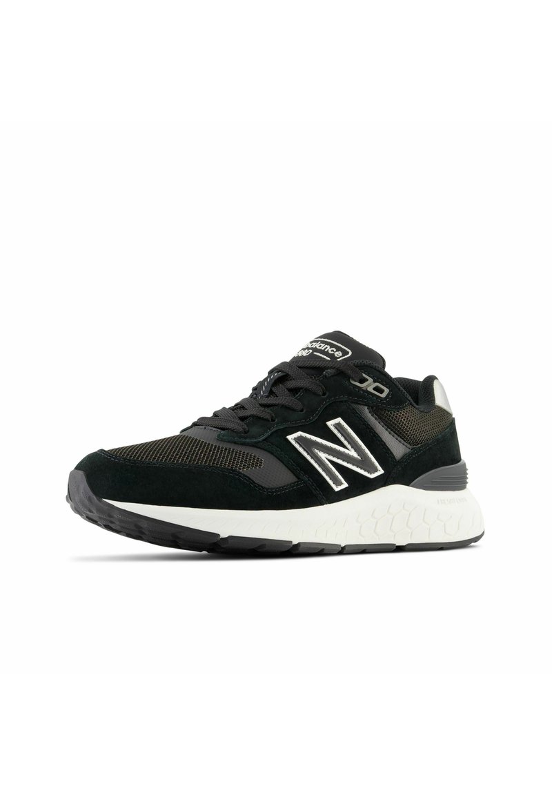 Chaussure de sport noire avec tige en mesh, accents en daim, logo réfléchissant, semelle rembourrée et motif de semelle texturé pour une meilleure adhérence.