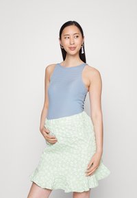 Top sem mangas azul à riscas combinado com uma saia de padrão floral em verde claro, com uma bainha com babados. O conjunto é projetado para roupas de maternidade.