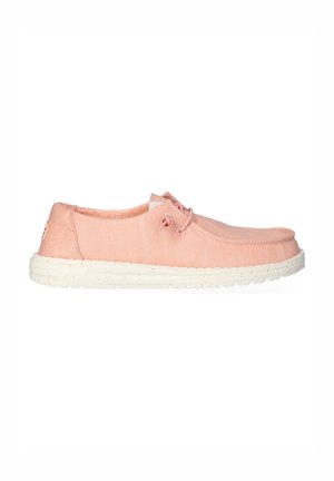 Chaussure décontractée façon slip-on rose clair avec semelle blanche tachetée et laçage latéral, conçue pour le confort et le port quotidien.
