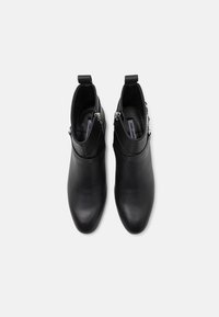 Botine negre din piele, cu vârf ascuțit, textură netedă, fermoare laterale și mânere decorative. Design minimalist, fără modele vizibile.