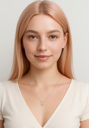 Collana d'argento con un pendente circolare, caratterizzato da dettagli intricati e una catena sottile. Il modello indossa un top crema a scollo a V. Pelle liscia e capelli lunghi e lisci.