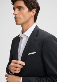 Blazer grigio scuro realizzato in tessuto testurizzato, caratterizzato da una vestibilità slim, rever a punta e un fazzoletto bianco nella tasca del petto.