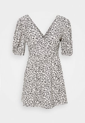 Robe à imprimé floral avec un col en V, des manches ballon et une taille cintrée. Fabriquée en tissu léger noir et blanc.