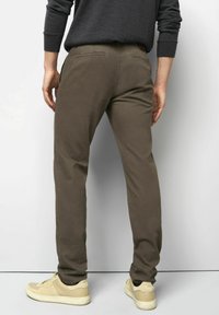 Bruine katoenen broeken met een slim fit, voorzien van een gestructureerde afwerking, achterzakken en gecombineerd met beige sneakers.