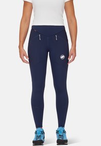 Legging bleu marine avec une taille haute, comprenant deux poches avant avec fermetures éclair et un logo sur la cuisse gauche. Fabriqué en matériau extensible.