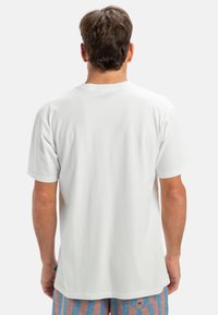 Bílá tričko s krátkým rukávem, kulatým výstřihem a jednobarevným zadním dílem. Vyrobeno z měkké bavlny. Tričko má volný střih. Žádné viditelné vzory.