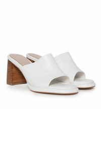 Hvide læder open-toe mules med en udskæringsdesign, der har en træblokhæl og en glat tekstur. Sål har en let kurve.