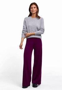 Szary sweter z okrągłym dekoltem i prążkowanymi mankietami, zestawiony z fioletowymi spodniami o szerokich nogawkach, charakteryzującymi się miękką teksturą i gładkim wykończeniem.