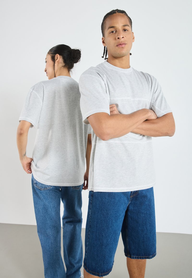 Lysegrå kortermet t-skjorte med rund hals og avslappet passform, sammen med blå denimshorts. Myk stoff med minimal detaljering.