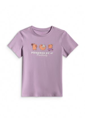 Dziewczyna ubrana w fioletowy t-shirt z grafiką, szare legginsy, białe skarpetki, trampki i szarą bluzę z kapturem zarzuconą na ramiona na jednolitym tle.