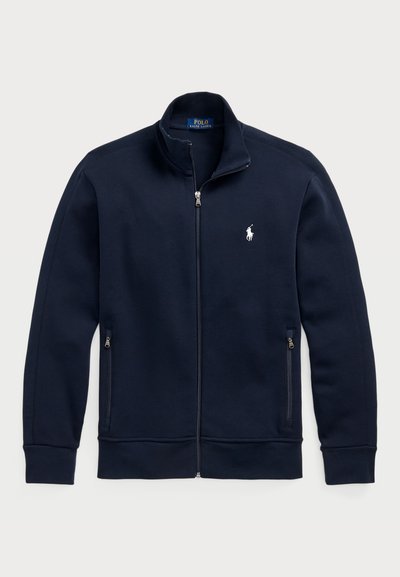 Sudadera con cremallera en color navy, hecha de tela suave, con un alto cuello, dos bolsillos laterales con cremalleras y un logo de polo en blanco en el pecho.