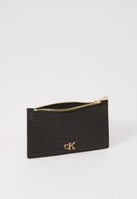 Portafoglio in pelle nera con effetto coccodrillo, dotato di una cerniera dorata, con un piccolo logo dorato sul fronte e una forma rettangolare elegante.