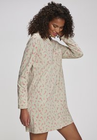 Nattkjole med lange ermer i lyst grønt stoff med sukkertøystangmønster. Har knappestolpe foran og en enkelt brystlomme. Myk tekstur.