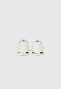 Hvite sneakers med en glatt lærfinish, med en såle i svart og hvitt stripete mønster og merket "JOOP!" på hælen.