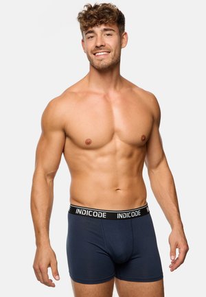 Navy blue boxer shorts with a black waistband featuring the brand name "INDICODE" in white. Soft fabric, close-fitting design.