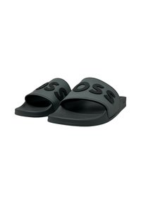 Sandales glissantes noires avec une large sangle ornée de lettres en relief. Fabriquées en matériau synthétique doux, avec une semelle plate et un design minimaliste.