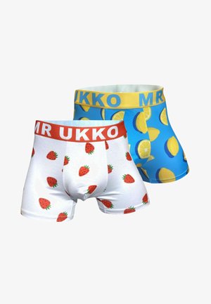 Dwie pary męskich bokserek, jedne białe z truskawkami i czerwoną gumką, drugie niebieskie z żółtymi cytrynami i żółtą gumką.