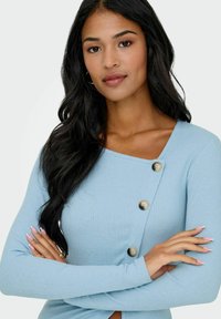 Jasnoniebieski prążkowany top z długimi rękawami, z kwadratowym dekoltem i guzikami po lewej stronie. Gładka faktura z dopasowanym krojem.