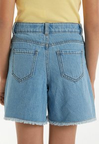 Shorts en denim taille haute de couleur bleu clair, avec un ourlet effiloché, deux poches arrière et des coutures contrastées le long des coutures.