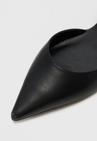 Černá kožená bota s špičatou špičkou a otevřeným bočním designem. Hladký povrch, štíhlý silueta a minimalistický vzhled. Bez viditelného kování.