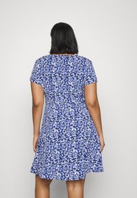 Vestuário estampado com flores em azul e branco, mangas curtas, corpete justo e saia rodada, feito de um tecido leve com uma textura suave.