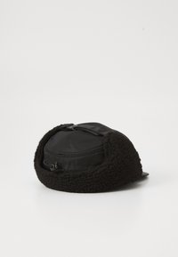 Cappello nero con un esterno in morbido pile e una parte superiore in tessuto liscio. Cinghia di regolazione centrale, visiera leggermente curva e forma arrotondata.