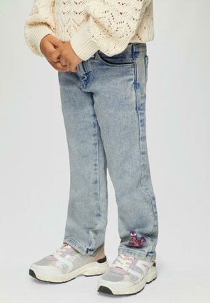 Lichtblauwe denim jeans met een rechte pasvorm, voorzien van een kleine paarse glinsterdetail op de linker enkel en zakken. Gedragen met multikleurige sneakers.
