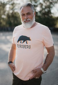 Lichtroze T-shirt met een zwarte beer grafiek en "FORSBERG" tekst, korte mouwen en een ronde hals ontwerp.