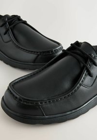Chaussures en cuir noir avec un bout arrondi, de fines coutures et un système de laçage, dotées d'une semelle en caoutchouc texturé pour une meilleure adhérence.