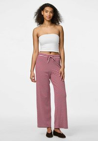 Randiga röda och vita vida byxor med dragsko i midjan, som är kombinerade med en åtsittande vit off-shoulder-topp. Mjuk tyg, avslappnad design.