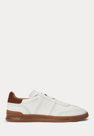 Hvid lædersneaker med brun sål og hæl, brogue-detaljer, snørebånd og Polo-logo prægede på siden og sålen.