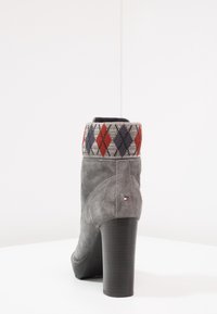 Botte pour la cheville à talon haut en nubuck gris avec un montant en laine présentant un motif argyle rouge, bleu et gris. Talon bloque noir.