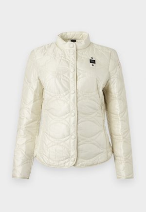 Bela prešita jakna z zapiranjem na pritisne gumbe, visokim ovratnikom, subtilnim vzorcem valovitih šivov in majhno črno-belo etiketo na prsih.