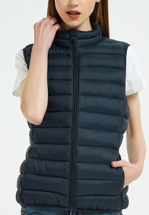 Gilet matelassé marine avec un design à coutures verticales, un col haut et une fermeture éclair à l'avant. Comprend deux poches latérales et une texture lisse et légère.