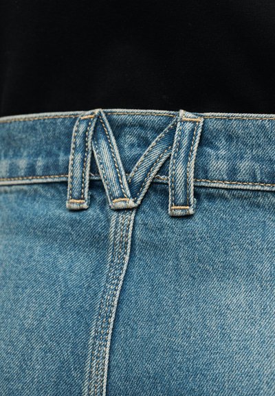 Ζώνη μέσης τζιν με μοναδικό σχέδιο θηλιάς ζώνης σχηματίζοντας το γράμμα "M" πάνω σε μαύρο φόντο τοπ.