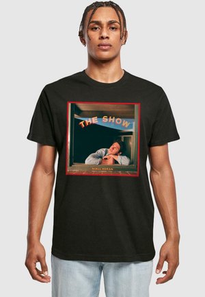 Sort t-shirt med et rektangulært grafisk motiv af en mand, der kigger ud af et vindue, med teksten "THE SHOW" ovenfor og "NIALL HORAN" nedenfor.