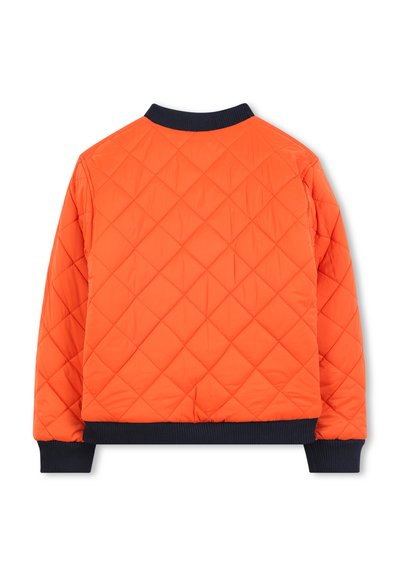 Veste orange matelassée avec un motif en losanges, dotée d'un col et de poignets en tissu côtelé noir. Le design met l'accent sur la chaleur et le confort.