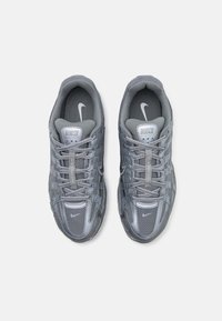 Grau Sportlichkeitsschuhe mit einem Obermaterial aus Mesh und synthetischen Überzügen. Zu den Merkmalen gehören Schnürsenkel, gepolsterte Zungen und strukturierte Sohle. Nike-Logo oben.