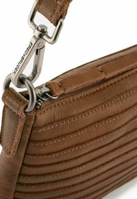 Brown leather bag with horizontal stitching, a metallic clasp, and a textured surface. Features a zipper along the top for closure.