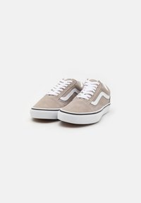 Semsket sneakers i lys taupe med hvite snører, kontrasterende sidestreker og en svart aksentlinje på gummisålen.