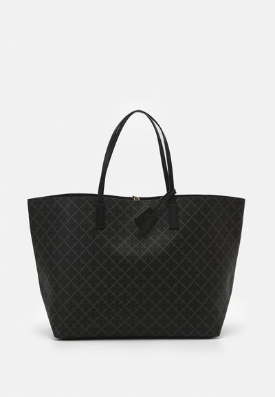 Large black tote bag made of patterned material, featuring long flat handles and a decorative tag. The design includes intersecting lines.