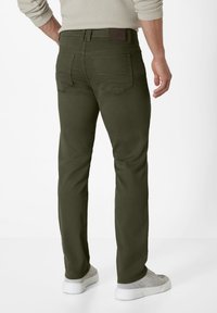 Olive green pants with a slim fit, featuring a smooth texture, back pockets, and a leather patch on the waistband. Paired with gray sneakers.
