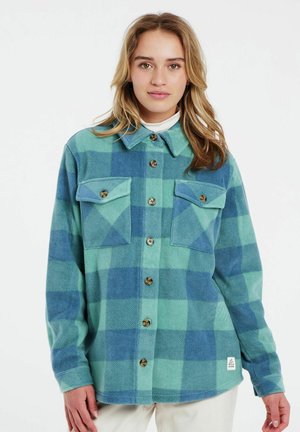 Camicia di flanella con pattern a quadri blu e verdi, dotata di due tasche sul petto, chiusura con bottoni, colletto e texture morbida.